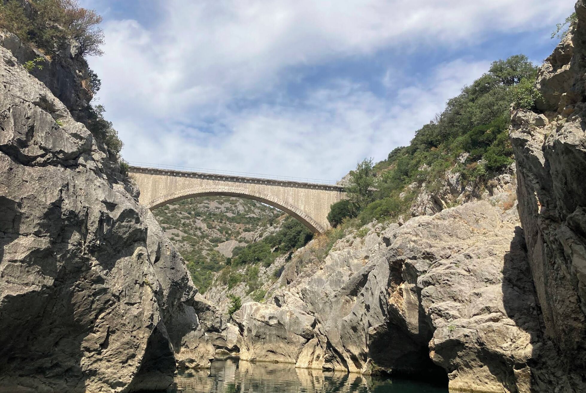 Un puente de piedra sobre un desfiladero rocoso con agua abajo.