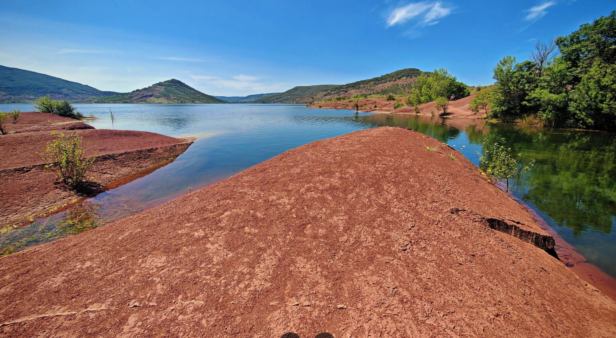A river with red soil banks and a clear blue sky.