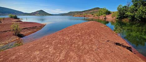 Un río con orillas de tierra roja y un cielo azul despejado.