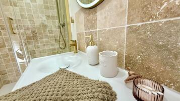 A bathroom with a white sink, gold fixtures, a beige towel, and a soap dispenser.