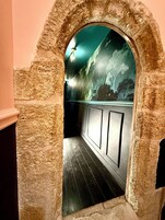 Un arco de entrada a una habitación con suelo de madera oscura y un muro decorado con un mural de árboles.