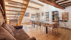 Een ruime eethoek met een houten tafel en stoelen, een trap en uitzicht op een rustieke stenen muur.