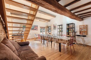 Un comedor amplio con mesa y sillas de madera, una escalera y vistas a una pared de piedra rústica.