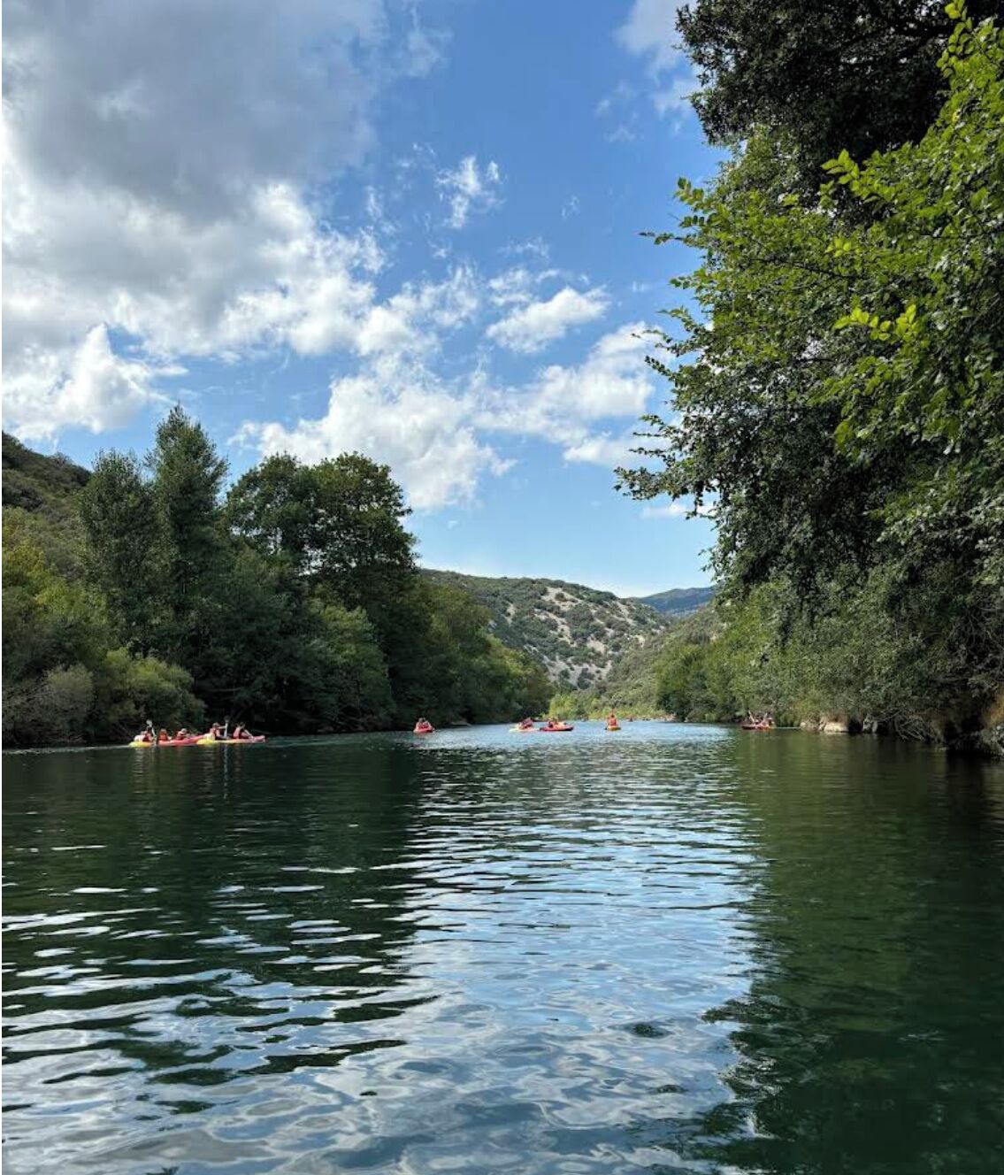 A river surrounded by lush greenery and hills.