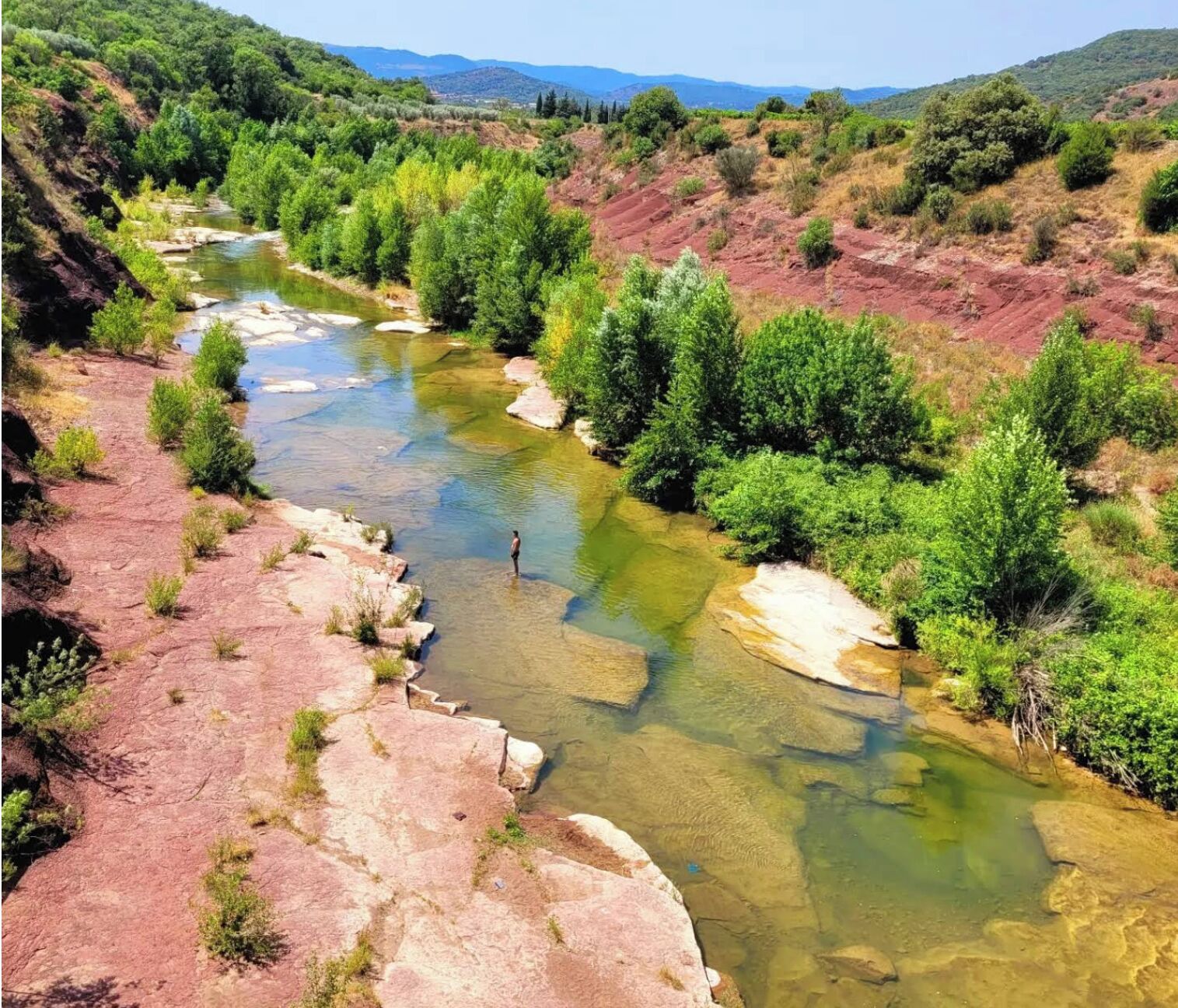 A river flowing through a rocky landscape with greenery on the banks.