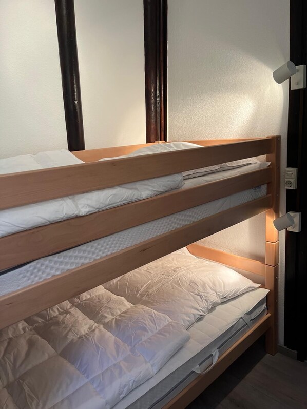 A bunk bed with three levels, each with a pillow and a mattress.