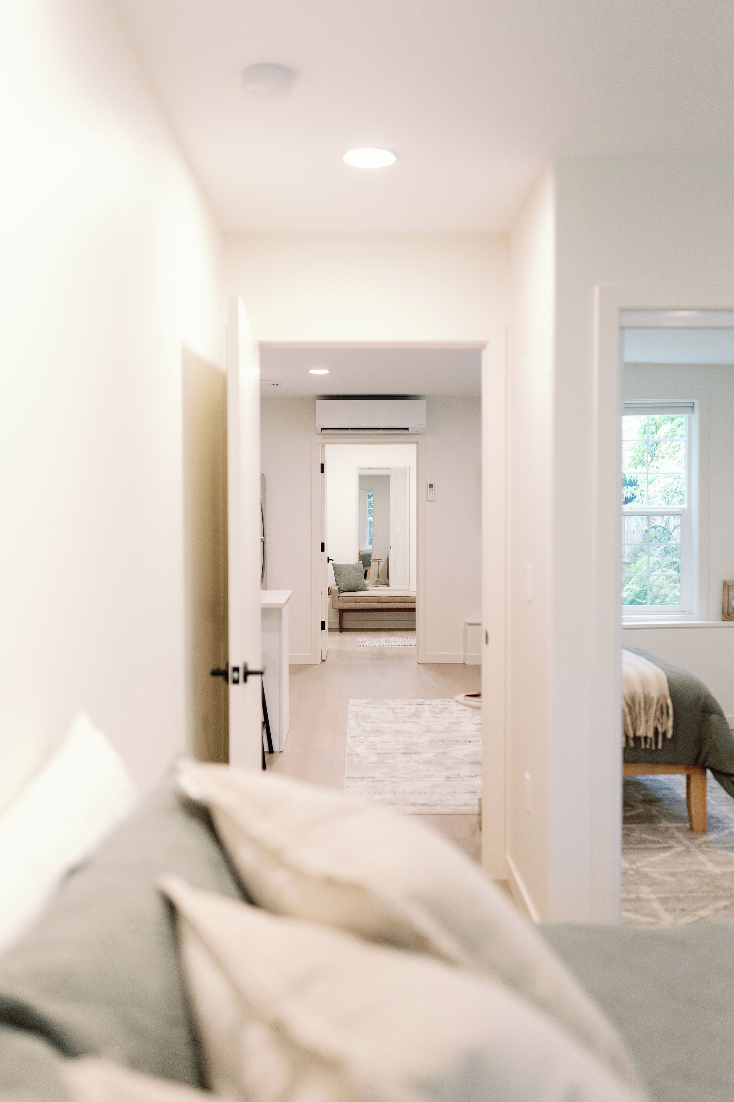 A hallway leading to a living area with a sofa and a window.