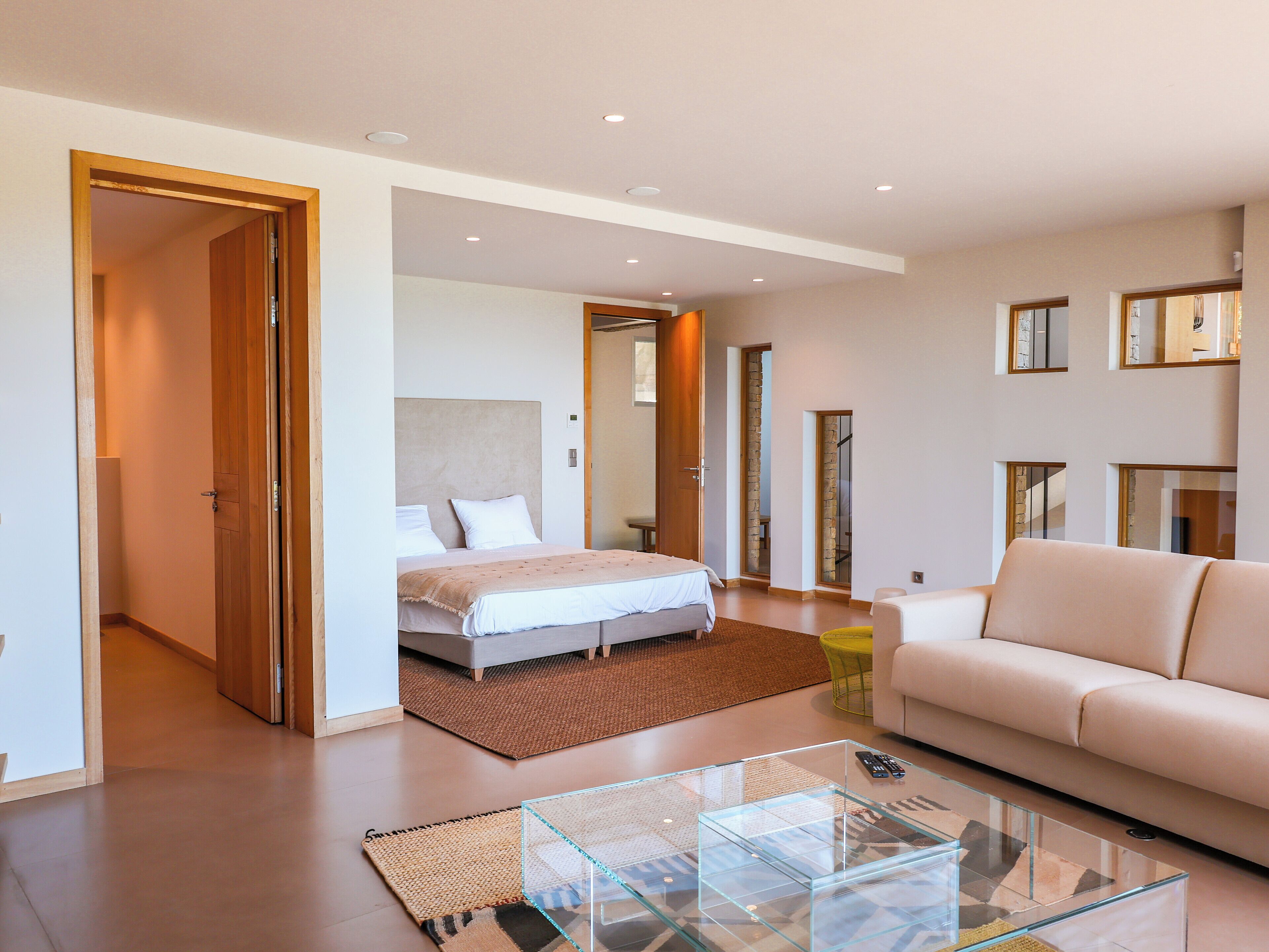 Una moderna camera d'hotel con un letto, un tavolino in vetro, una poltrona e vista all'esterno.