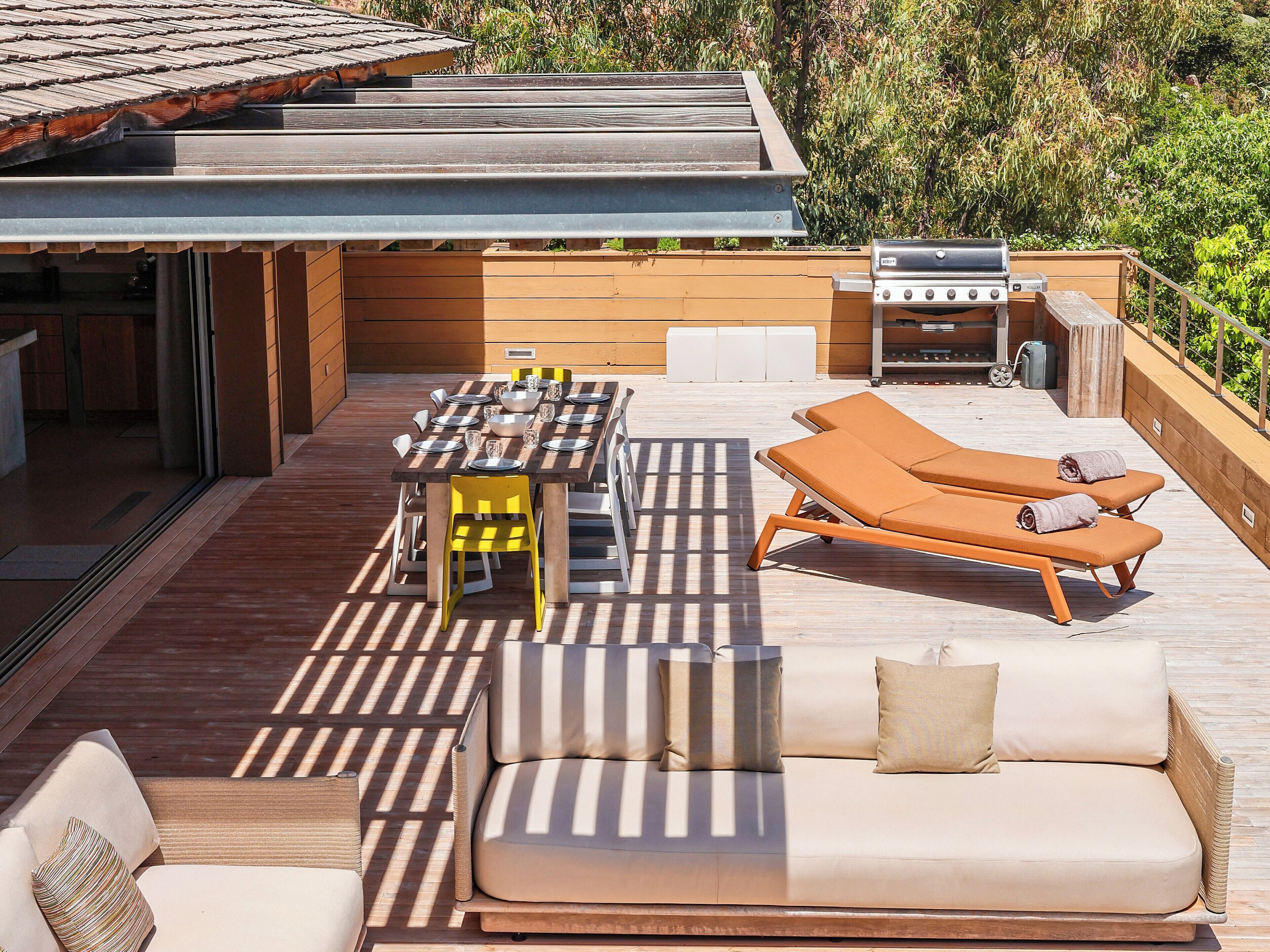 An outdoor patio with a dining table, lounge chairs, and a grill.