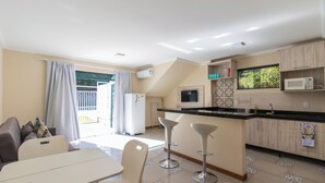 A modern kitchen with a dining area, a refrigerator, a microwave, and a window with a view of greenery.