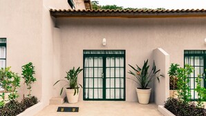 A building with a beige facade, green-framed windows, and potted plants.