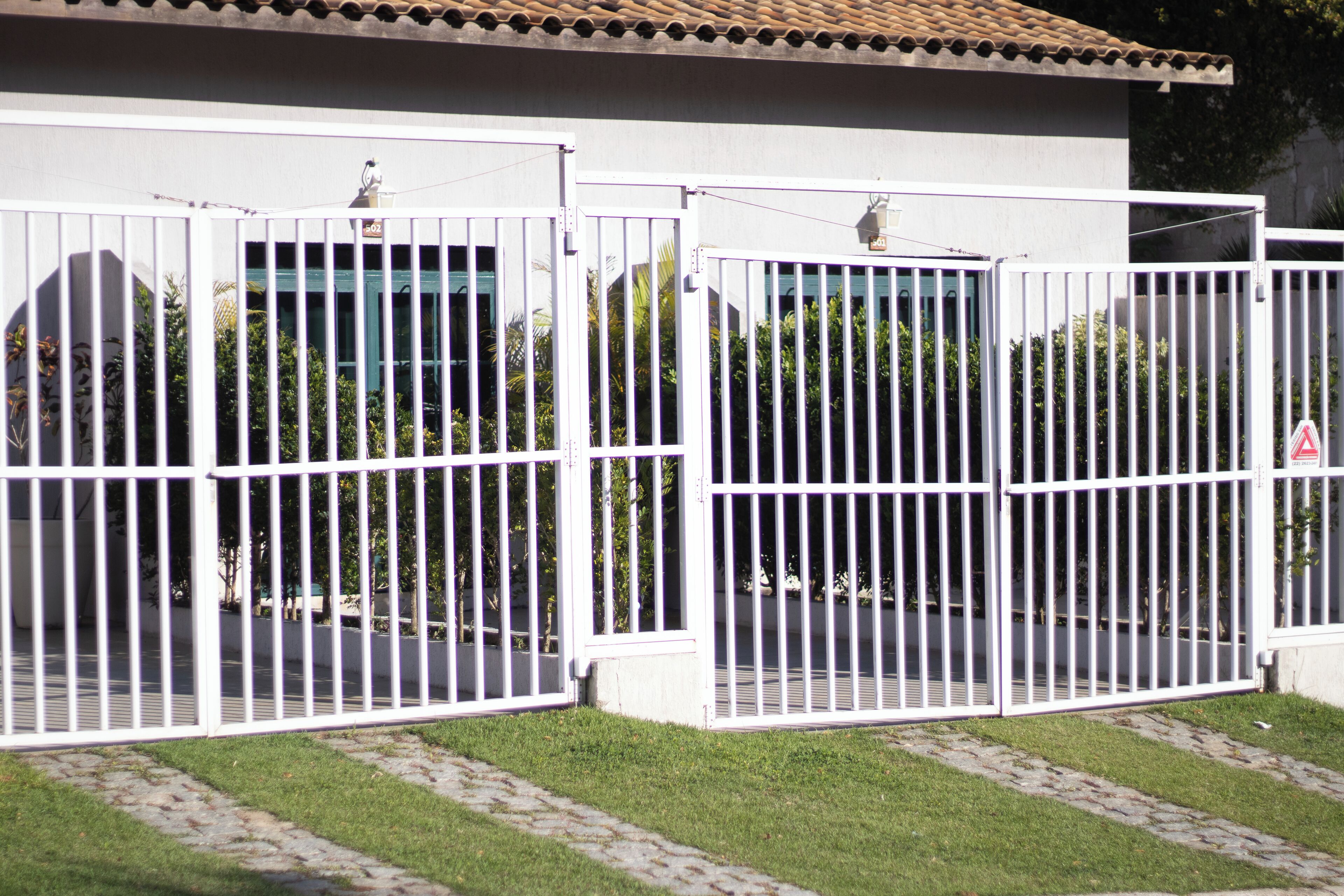 A gated entrance with a tiled roof and a paved pathway leading to a building.