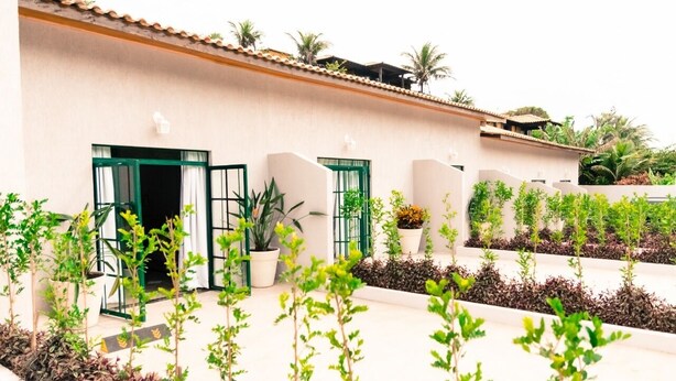 A building with a tiled roof, green-framed windows, and potted plants in front.