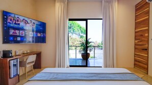 A hotel room with a bed, a desk, a TV, and a balcony with a plant. - Hotel Manglar  (Puerto Escondido)