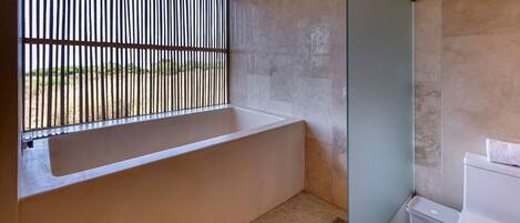 A bathroom with a bathtub, a toilet, and a shower area.