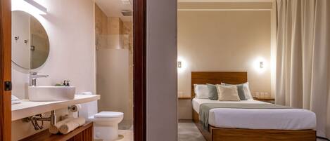 Un dormitorio moderno con una cama de madera, un espejo grande, un lavabo blanco y un inodoro.
