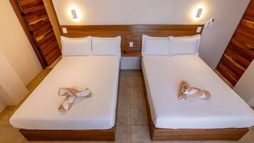 Habitación doble con dos camas, cada una con cabecero de madera y ropa de cama blanca.
