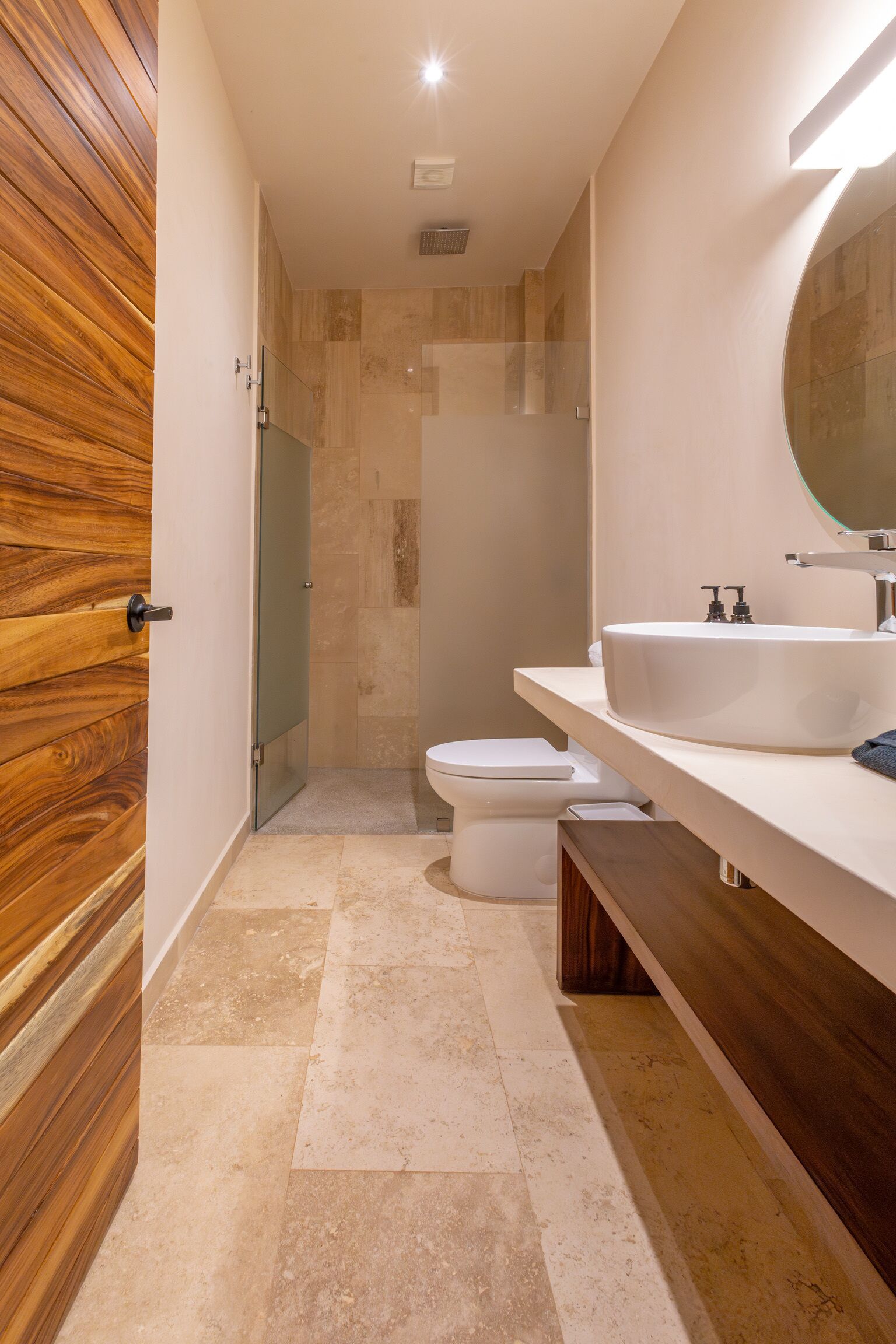 Un baño moderno con tocador de madera, un espejo grande y zona de ducha.