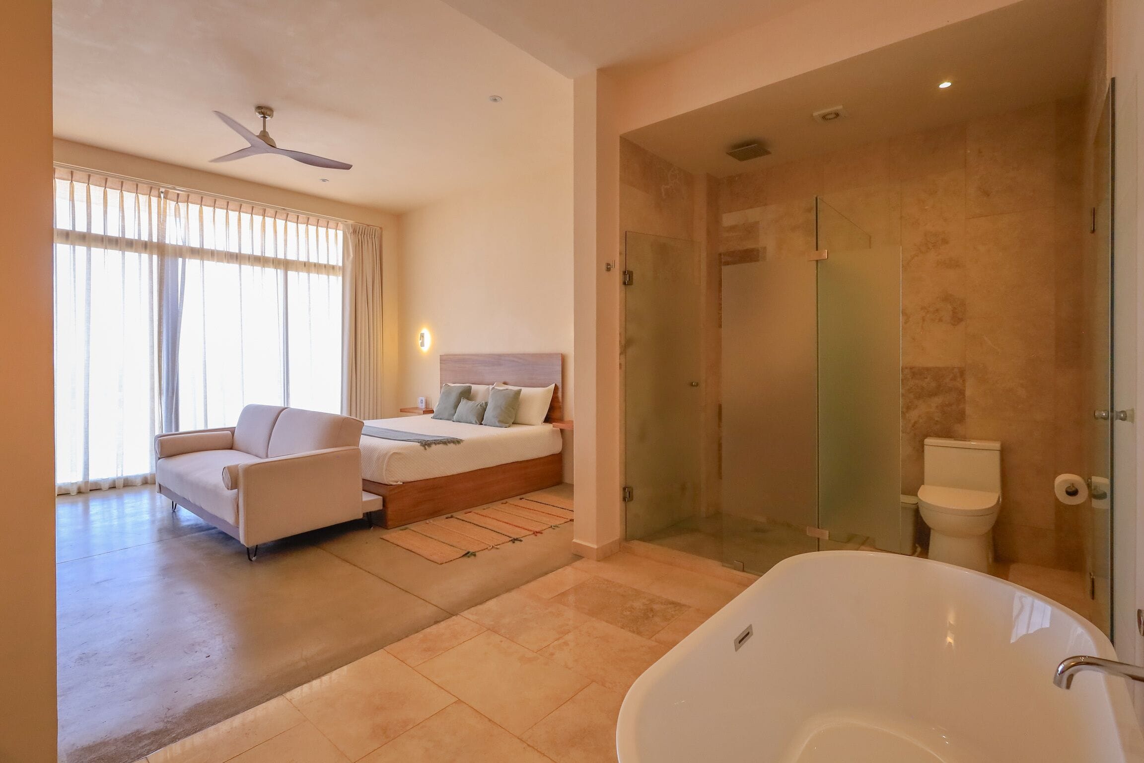 Une chambre d’hôtel moderne dotée d’un grand lit, d’un canapé, d’une douche en verre et d’une baignoire.