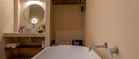 Ein modernes Badezimmer mit einer freistehenden Badewanne, einem Waschtisch mit Spiegel und einem Handtuchhalter.