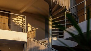 A modern interior with a spiral staircase, a balcony, and a wooden fence. - Hotel Manglar  (Puerto Escondido)