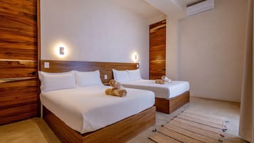 Habitación de hotel con dos camas, cabeceros de madera y una alfombra pequeña.