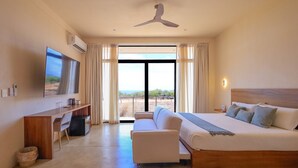 A modern hotel room with a large bed, a desk, a TV, and a view of the outdoors. - Hotel Manglar  (Puerto Escondido)