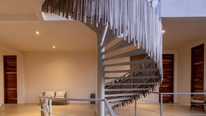 A modern interior with a spiral staircase, a lounge area with seating, and a dining space. - Hotel Manglar  (Puerto Escondido)