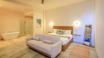 Un dormitorio moderno con cama, sofá, bañera y un espejo grande.