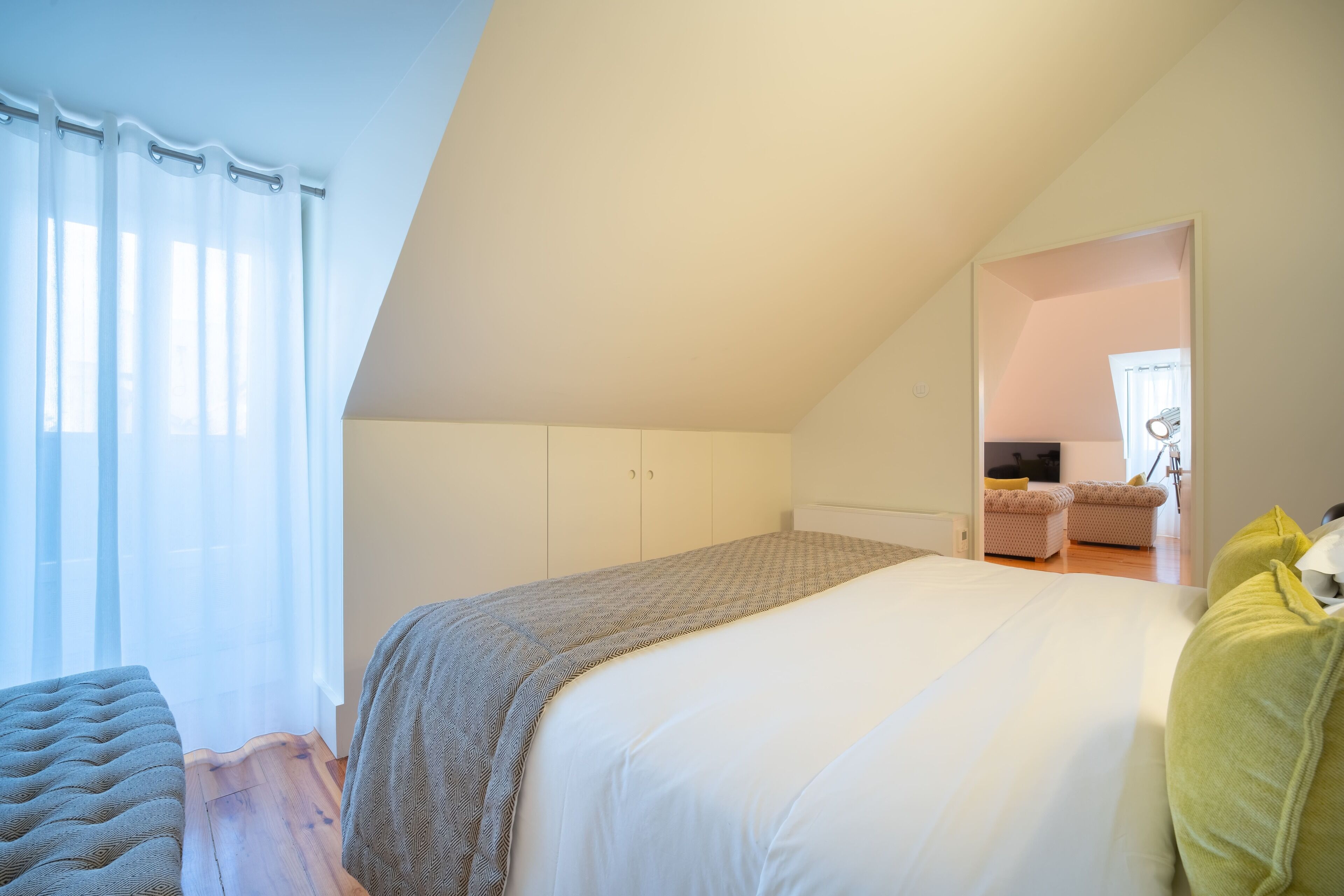 Een slaapkamer met een bed, een bankje en een kledingkast.