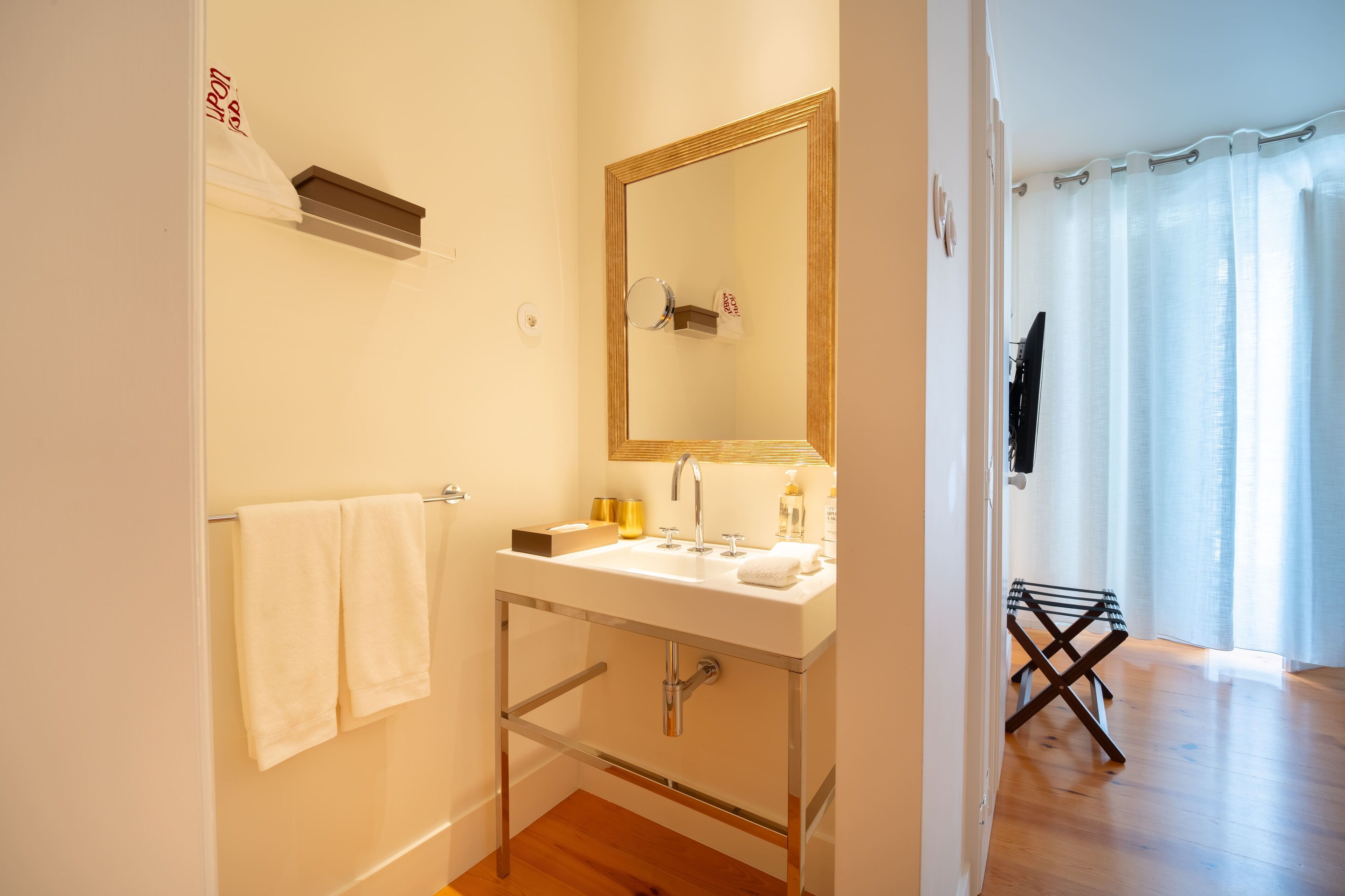 A bathroom with a white sink, mirror, and towel rack.