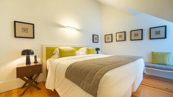 A bedroom with a bed, bedside table, lamp, and wall-mounted pictures.