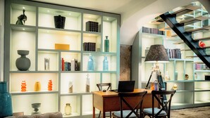 A modern interior with a wooden desk, two chairs, and a bookshelf filled with various decorative items. - Once Upon Lisboa (Lisbon)