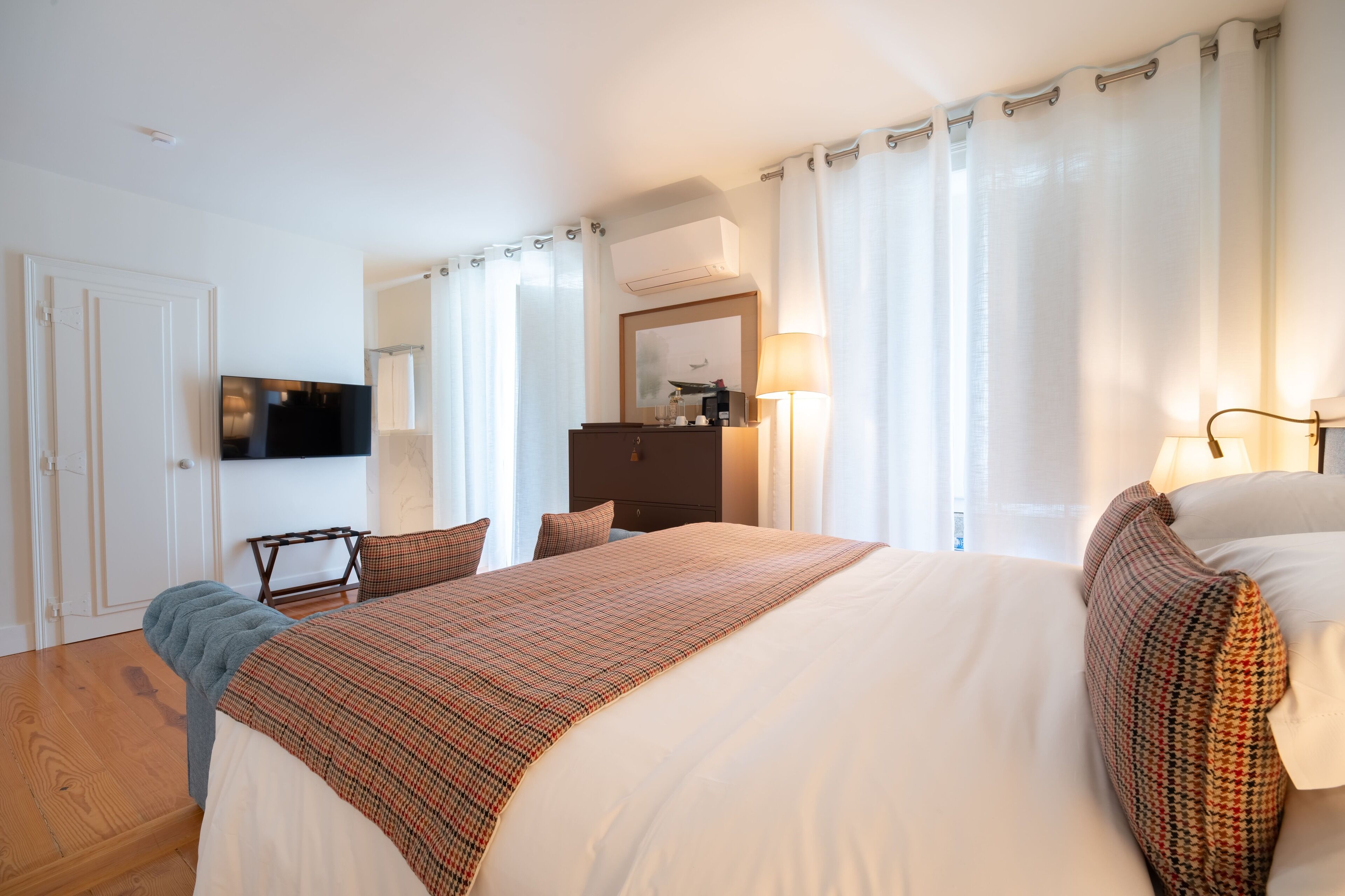 Habitación de hotel con una cama grande, televisión, escritorio y armario.
