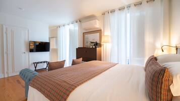 Habitación de hotel con una cama grande, televisión, escritorio y armario.