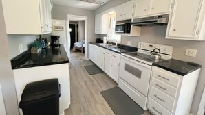 A modern kitchen with white cabinets, a black countertop, a stainless steel range hood, and a built-in microwave. - Charming Mpls Escape - Sleeps 14 (Minneapolis)