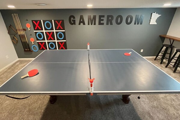 A ping pong table in a room labeled "GAMEROOM" with a wall decoration of Xs and Os, and a map of Minnesota. - Charming Mpls Escape - Sleeps 14 (Minneapolis)
