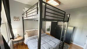 A bunk bed with a grey quilt, a bedside table with a lamp, and a small plant. - Charming Mpls Escape - Sleeps 14 (Minneapolis)
