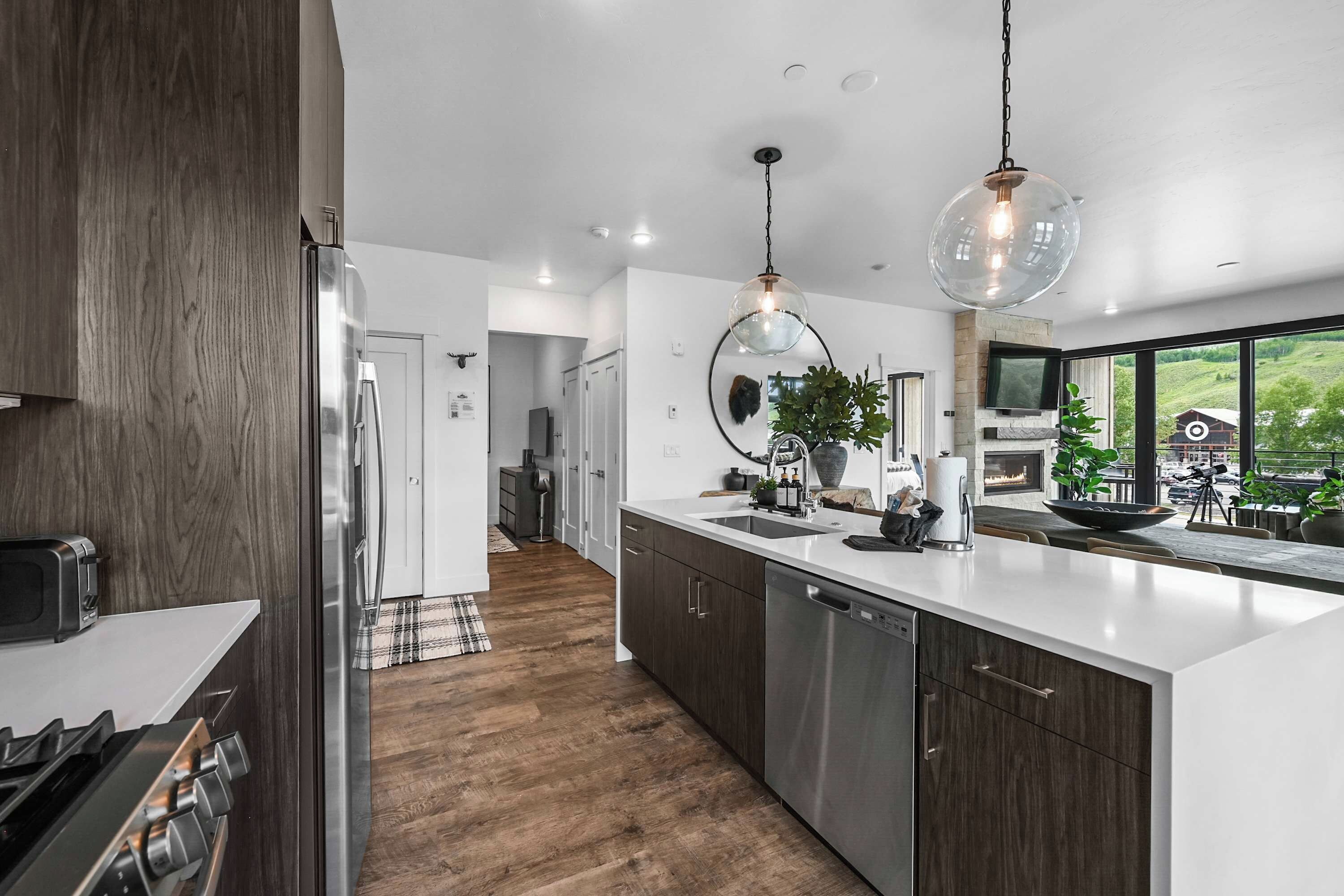A modern kitchen with a large island, stainless steel appliances, and a view of the outdoors.