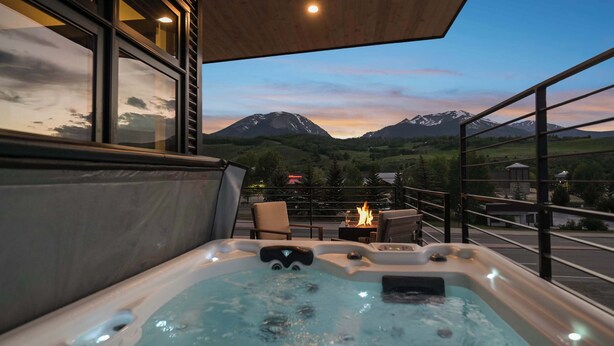 Ein Whirlpool mit Blick auf die Berge, ein Sessel und ein Feuertisch.