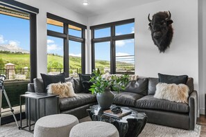 A modern living room with a leather sofa, a coffee table, and a mounted animal head.
