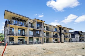 A modern multi-story building with balconies, large windows, and a clear sky.