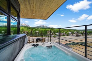 A hot tub with a mountain view, wooden ceiling, and a balcony with a railing.