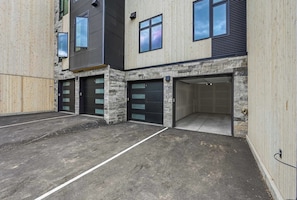 A modern building with two garage doors and a concrete driveway.