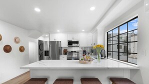 Una cocina moderna con armarios blancos, electrodomésticos de acero inoxidable y una isla grande con taburetes.