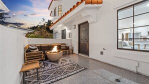 Un espacio exterior acogedor con una fogata, mobiliario de mimbre y un tapete estampado.