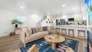 Una sala de estar moderna con un sofá, una mesa de centro y una cocina al fondo.