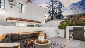 Une terrasse extérieure avec un foyer, un canapé et un barbecue.