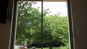 A room with a large sliding glass door leading to a view of trees and a small house. - Eth Vergèr esvanit *** - vacation home 8 persons (Juzet-de-Luchon)