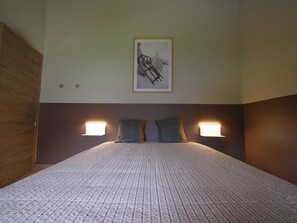 Ein Schlafzimmer mit einem Bett, zwei Wandleuchten und einem gerahmten Bild an der Wand.